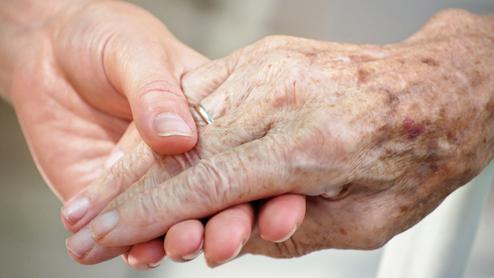 Nahaufnahme zweier Hände, eine ältere und eine jüngere, die sich liebevoll halten.